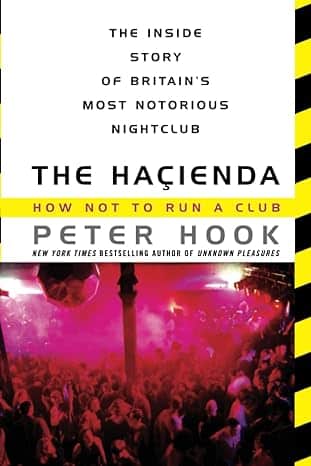 The book cover of "The Haçienda: How Not to Run a Club" by Peter Hook features bold black and yellow hazard stripes bordering the top and bottom. Above a photo of a crowded nightclub with vibrant red and pink lighting, the text is prominently displayed.